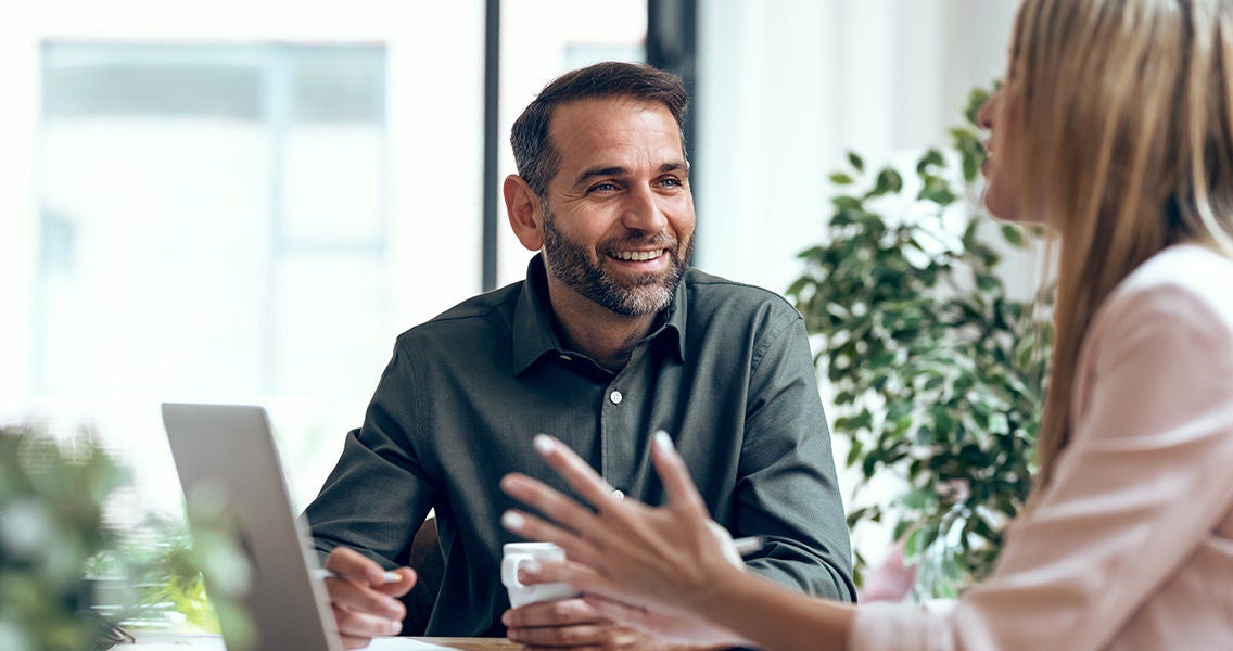 Man and woman sitting at a desk working on a laptop together