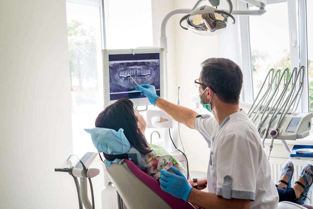 Dentist reviewing images with a patient in a room and pointing to the teeth