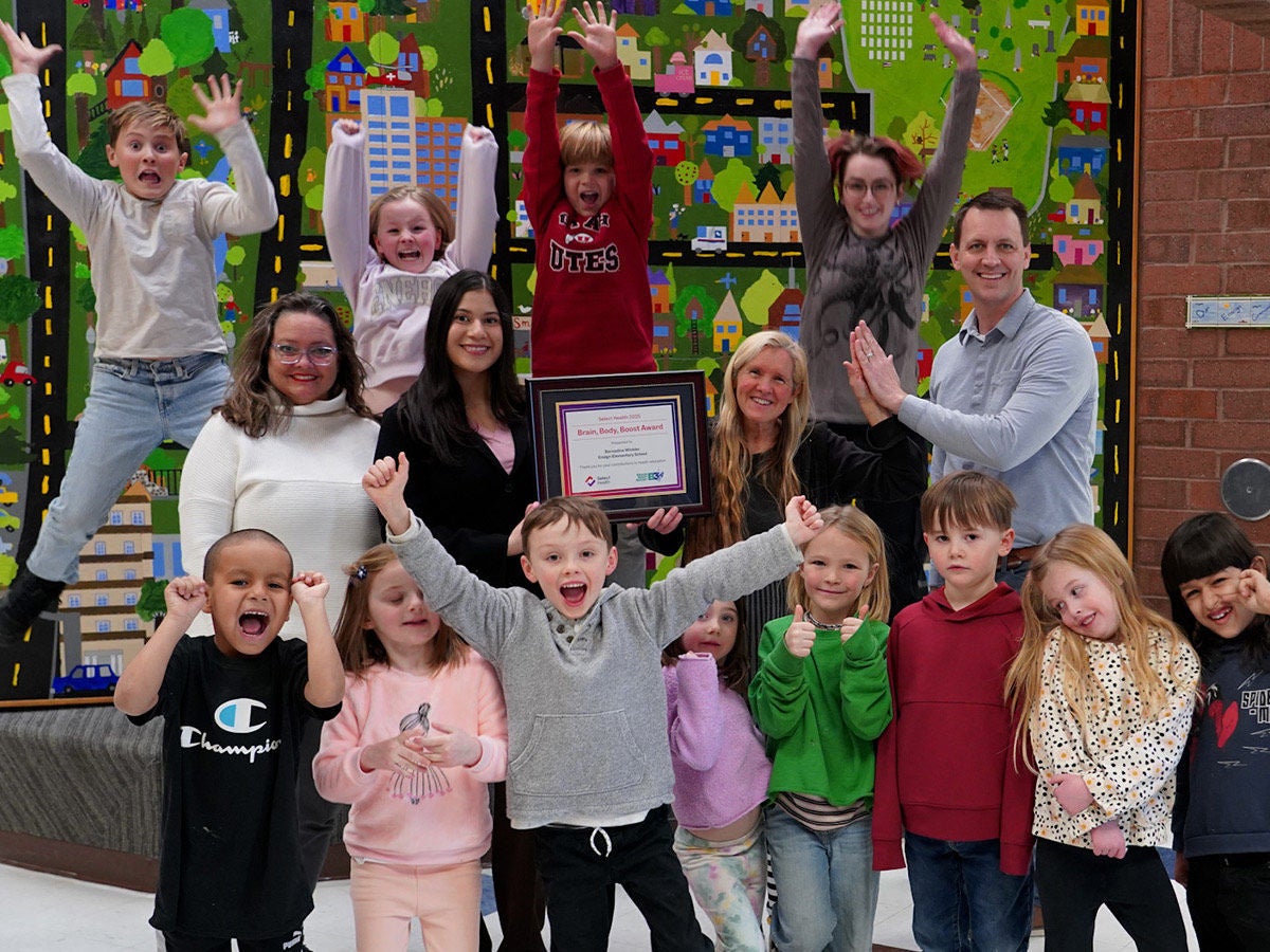 Picture of classroom jumping and SH showing an award with teachers