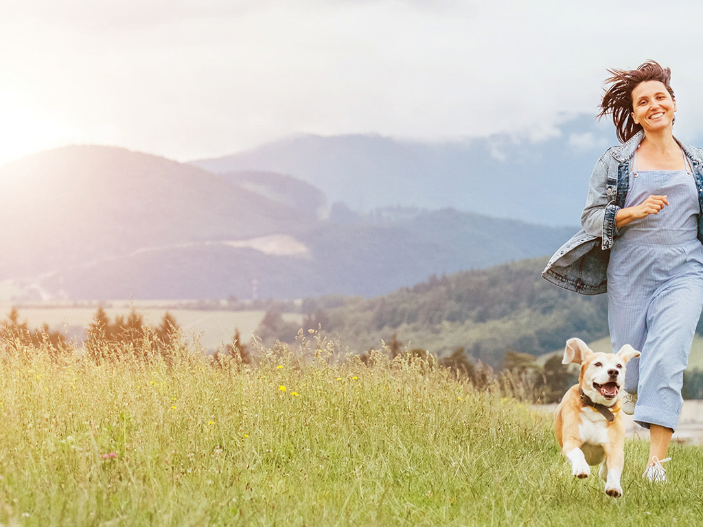 Woman running in a field with her dog