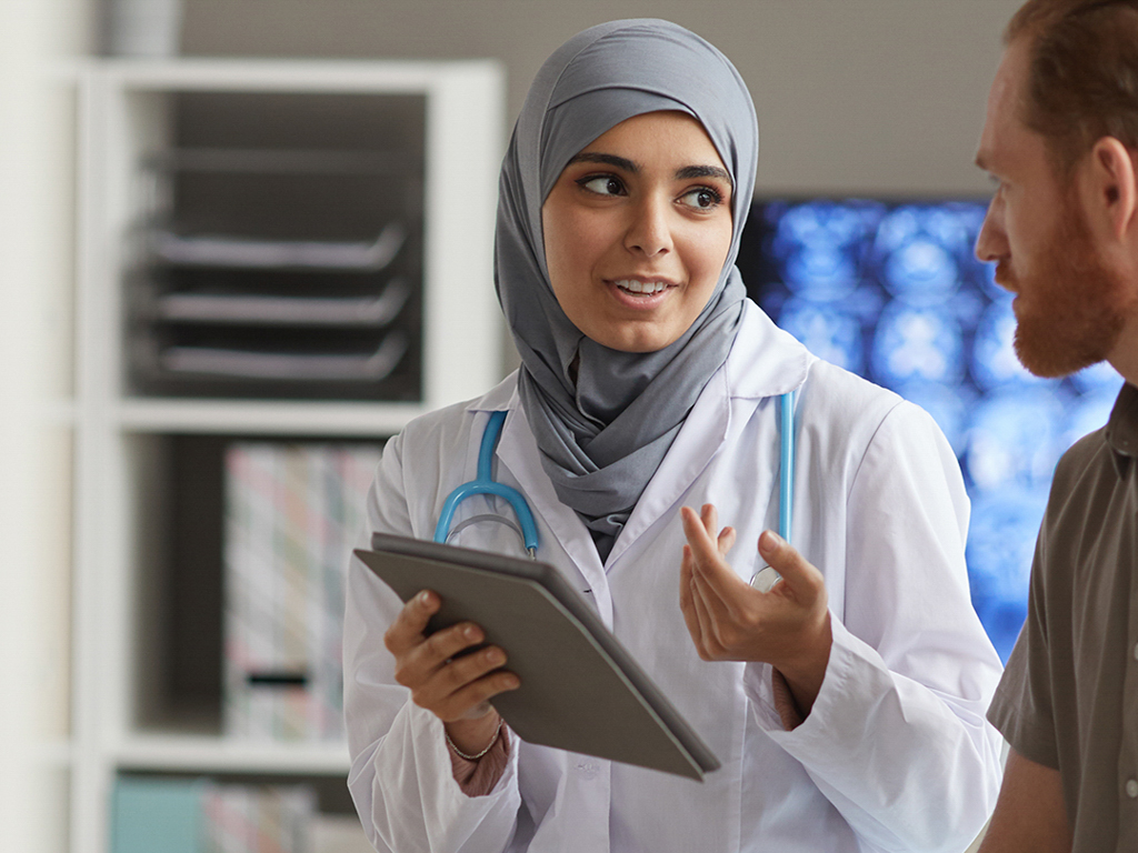 a female doctor explains something to her male patient using a digital tablet