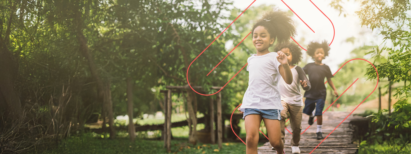 three children outside running on a trail smiling