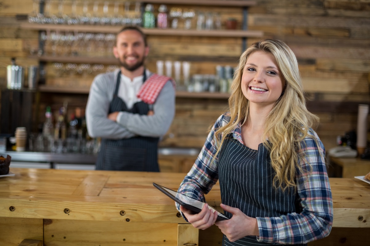 Portrait of smiling waitress standing with digital tablet