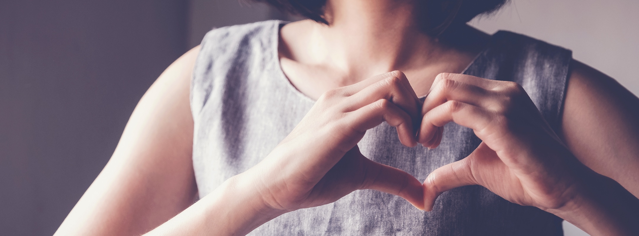 Happy Asian young woman making her hands in heart shape, heart health insurance, social responsibility, donation charity concept, world heart day