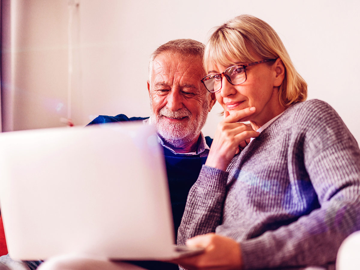 A photo of a couple looking at their computer screen.
