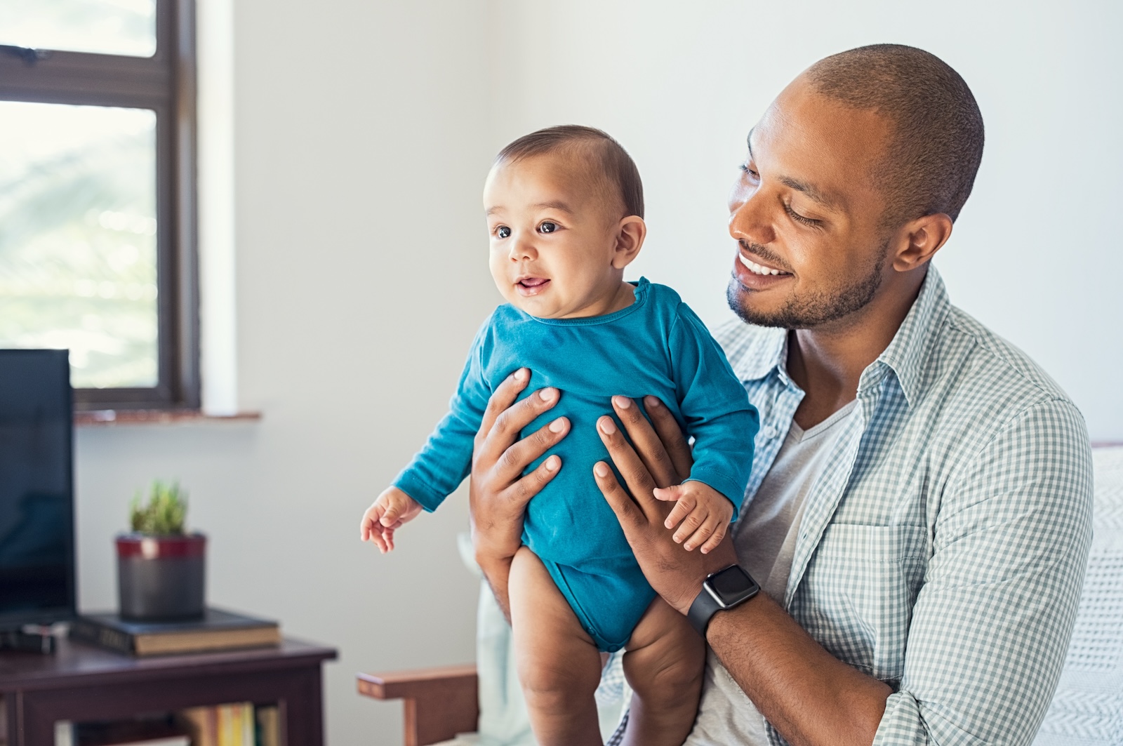 Happy black father and his baby having fun at home. Proud african father holding toddler in arms and playing. Smiling dad loving his cute son.