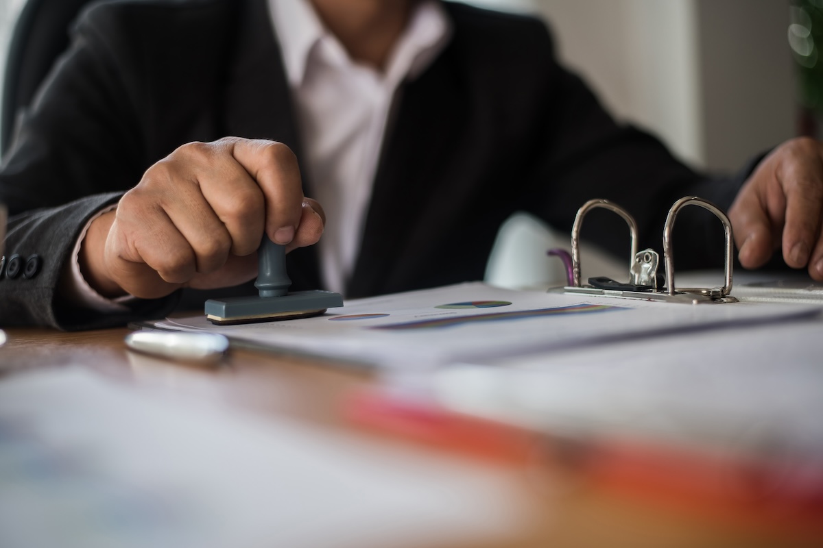 Businessman hand pressing rubber stamp approved on business contract document