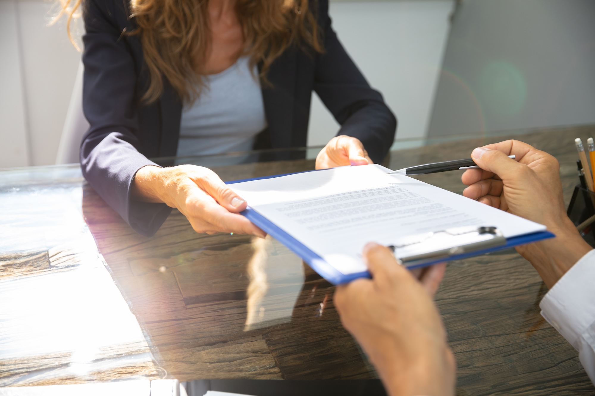 Handing a woman a clipboard and a pen for her to sign a document.