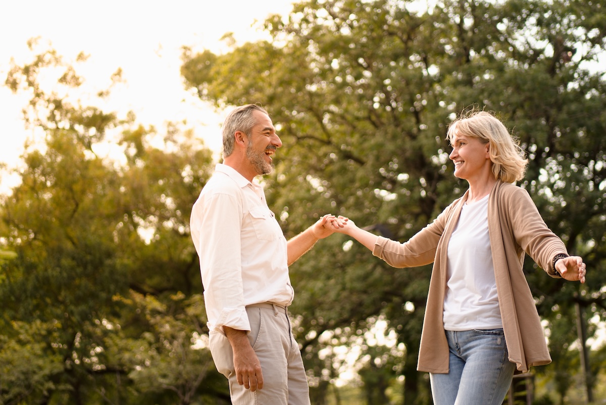 senior couple dancing and looking at each other in the park