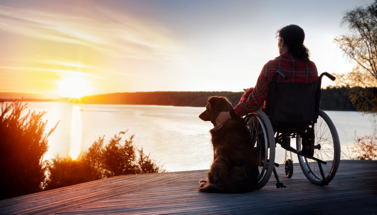 Woman in wheelchair with her dog at sunset